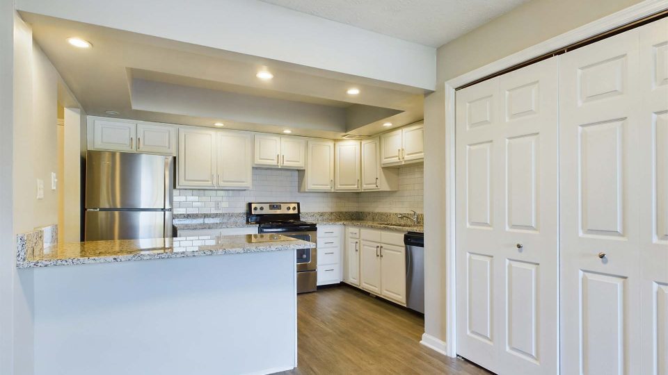 a kitchen with white cabinets and white appliances at The Edgewater